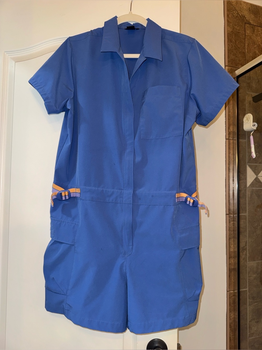 Cotopaxi Royal Blue Short-Sleeve Utility Romper with Orange Accents.